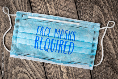 face masks required - text on a disposable mask, business sign during the coronavirus covid-19 pandemic and social distancing