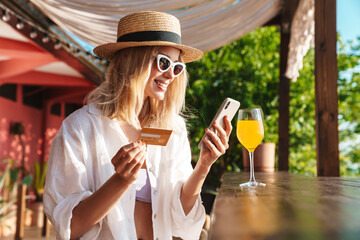 Sticker - Image of joyful nice woman holding credit card and using cellphone