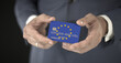 © Alexey Novikov - Businessman takes plastic bank card with printed flag of the European Union in his hands, fictional numbers