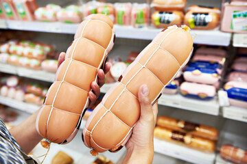 Wall Mural - Boiled sausage in hands buyer in shop