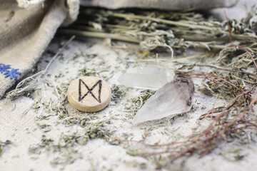 Scandinavian wooden rune Dagaz, Daeg on a rough linen cloth with amethyst crystalline, rock crystal and dried wormwood