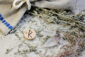 Scandinavian wooden rune Raidu, Raido on a rough linen cloth with amethyst crystalline, rock crystal and dried wormwood