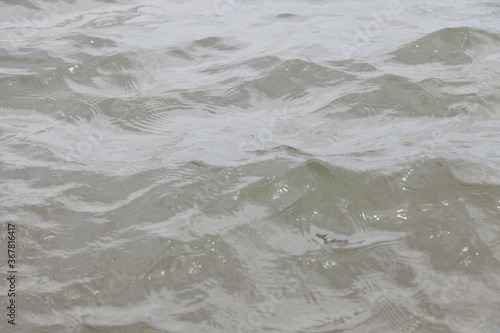 Cuadros en Lienzo Close-up of a river with undulating waves with muddy gray water in cloudy weather