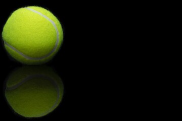 Wall Mural - Closeup shot of the reflection of a tennis ball on a reflective black surface