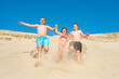 © Andrii - Family running on the beach sand on a sunny summer day. Family games on vacation. Sports and active lifestyle concept.