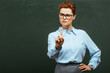 strict teacher in eyeglasses showing stop gesture while standing near chalkboard