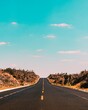 © Javier Rodriguez/Wirestock - Vertical shot of empty road under blue sky and white clouds