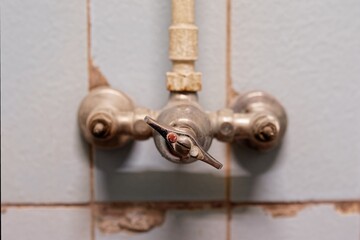 Sticker - Soft focus of an old wall mounted brass faucet on tiles