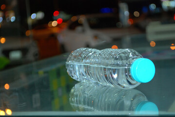 Mineral drinking water plastic bottle laying and reflecting closeup using soft focus blurry background.beautiful blurry colorful lights view.