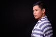 © Ranta Images - Portrait of young Asian man against black background