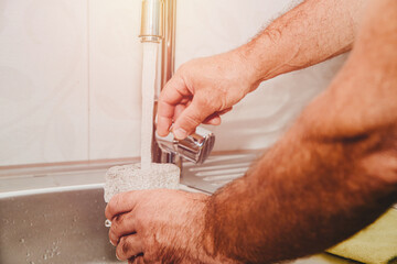 Wall Mural - Pouring water from the tap. The man pours water into a glass in the kitchen using the tap.