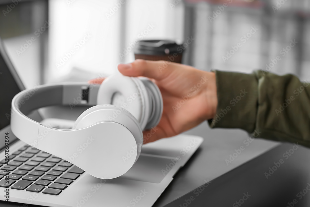 Man with headphones and laptop working in office, closeup