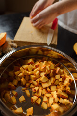 Woman chopping pumpkin on kitchen board, only hands visible. Autumn seasonal vegetables cooking. Healthy eating habits, organic vegetarian food concept.