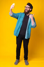 Full Length Photo Of Happy Man With Beard Taking Selfie Over Yellow Background.