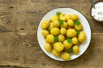 Wall Mural - Young boiled potatoes with parsley on a rustic background