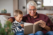 Grandfather reading fairy tales book to cute boy