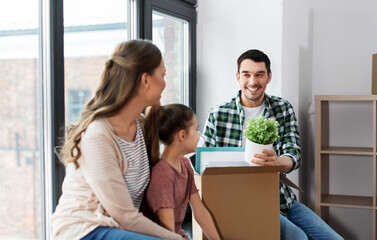 Canvas Print - mortgage, family and real estate concept - happy mother, father and little daughter with stuff in boxes moving to new home