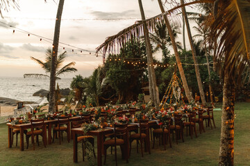 Set tables for a wedding dinner in a tropical garden. Concept of tropical beach wedding. Romantic sunset light