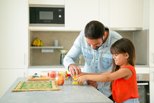 Joyful Young Dad And Daughter Enjoying Cooking Together. Girl And Her Father Squeezing Lemon Juice At Kitchen Counter. Family Cooking Concept