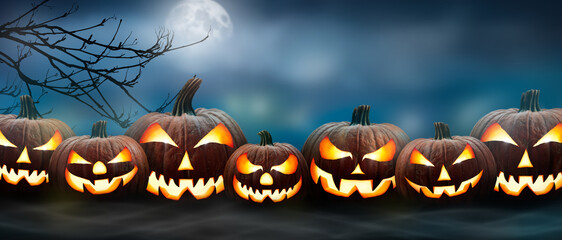Wall Mural - seven spooky halloween pumpkin, jack o lantern, with an evil face and eyes on the grass with a misty