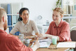 © AnnaStills - Group of business colleagues sitting at the table and talking to each other during business meeting at office