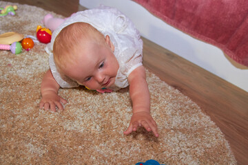 lying baby pulls to the toy,baby lying on the carpet reaches for a toy