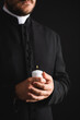 © LIGHTFIELD STUDIOS - cropped view of bearded priest holding burning candle in hands isolated on black