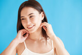 Fototapeta Na ścianę - Lovely young woman with healthy smooth skin against blue background