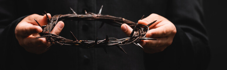 Wall Mural - horizontal crop of priest holding wreath with spikes isolated on black