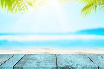 Poster - blur tropical beach with bokeh sun light wave and palm tree on empty old wood table abstract backgro