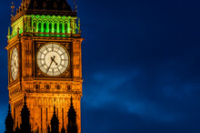 Big Ben Clock Face At Night With Silhouette Of Houses Of Parliament In The Foreground.