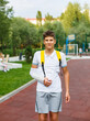 © Natali - Teenager with broken arm next to sports ground. Boy in white t shirt with hand splint in a arm sling for support and reducing pressure on neck. Injury, traumas, accident by kids