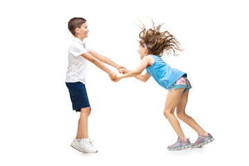 Wall Mural - Happy kids, little and emotional caucasian boy and girl jumping and running isolated on white background. Look happy, cheerful, sincere. Copyspace for ad. Childhood, education, happiness concept.