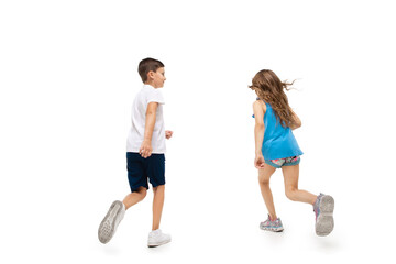 happy kids, little and emotional caucasian boy and girl jumping and running isolated on white backgr