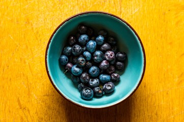 Wall Mural - Top view of a bowl filled with blueberries on a wooden surface