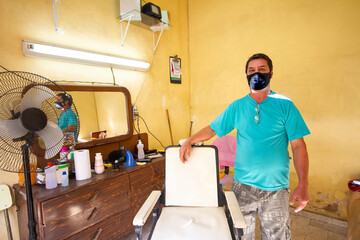 Barbeiro usa máscara de proteção contra coronavírus em seu ambiente de trabalho, em Guarani, Minas Gerais, Brasil.