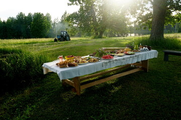 Wooden table under oaks with many traditional Latvian food. Old Latvian culture tradition LIGO. Midsummer night celebrating in Latvia.               