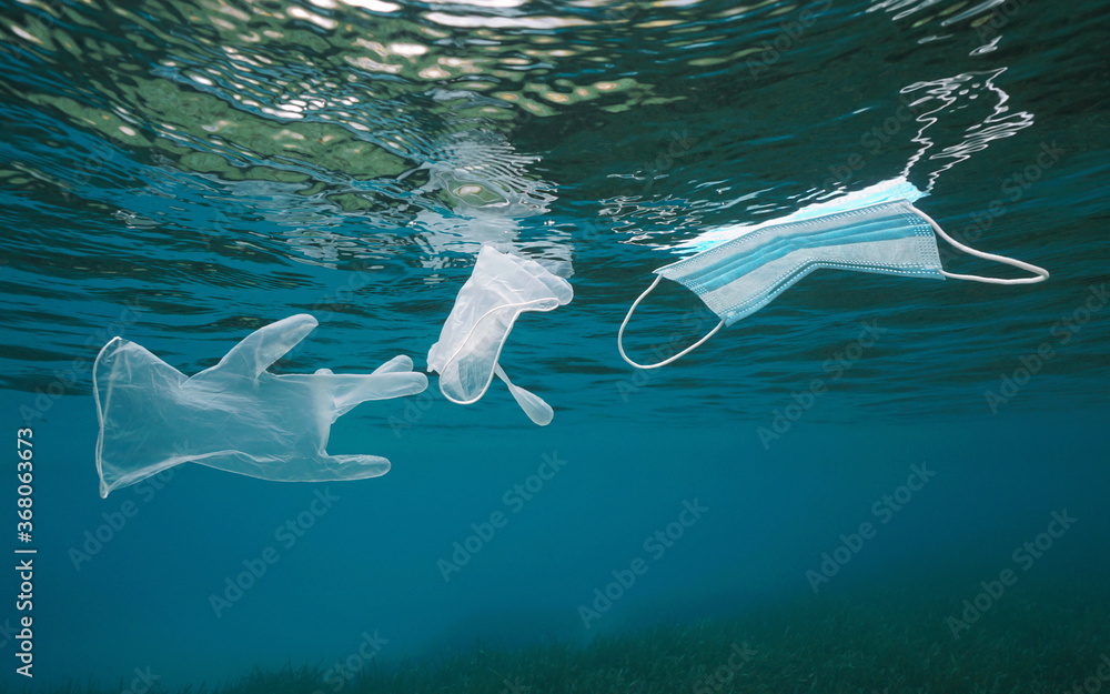 Plastic waste pollution in the sea since coronavirus COVID-19 pandemic, gloves with a face mask floating under water surface - obrazy, fototapety, plakaty 