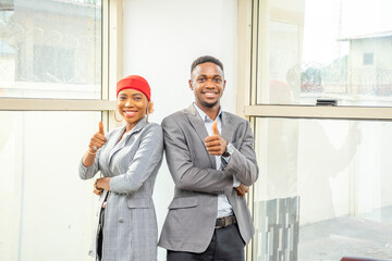 Wall Mural - two young african businesswoman and businessman giving thumbs up together