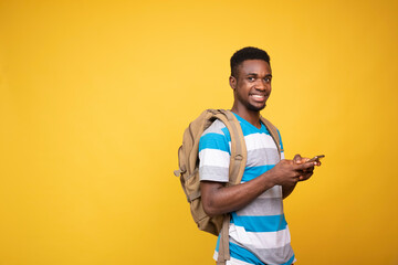 Wall Mural - a young black man carrying a backpack using his mobile phone, smiling