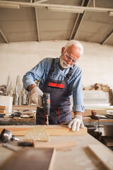 Waist up portrait of a carpenter drilling