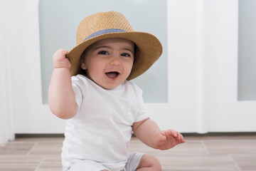 Wall Mural - baby playing with a straw hat 