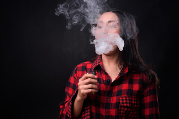 Wall Mural - Young beautiful Asian woman vaping against black background