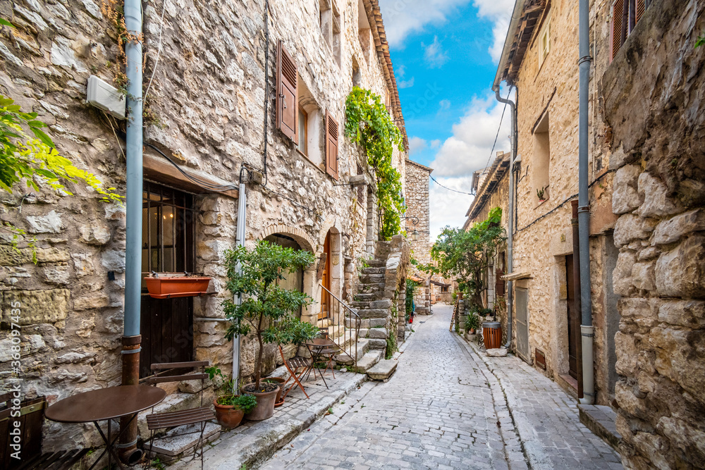 A picturesque back street of homes and apartments in the medieval village of Tourrettes Sur Loup in the Alpes_Maritimes area of Southern France. - obrazy, fototapety, plakaty 