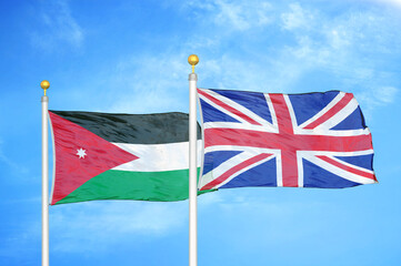 Jordan and United Kingdom two flags on flagpoles and blue cloudy sky