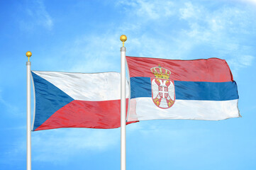 Czech and Serbia two flags on flagpoles and blue cloudy sky