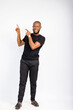 © Courage - young black handsome man standing and pointing at something towards his top right corner