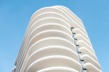 Architecture, exterior facade abstract view of modern residential, apartment, condo, condominium building wall with lights and shadows with wave shapes isolated against blue sky