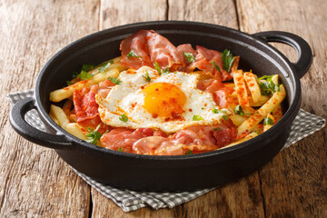 Delicious food fried egg with French fries and jamon close-up in a plate on the table. horizontal