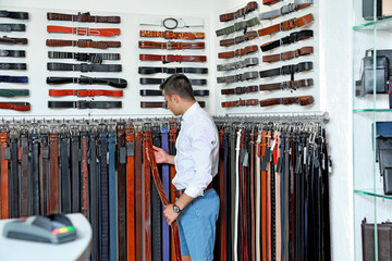 Man choosing belts in modern store